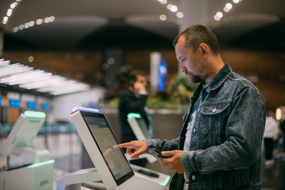 Een man staat bij de ingang van een event aan een touchscreen om onsite tickets te bestellen en te betalen.