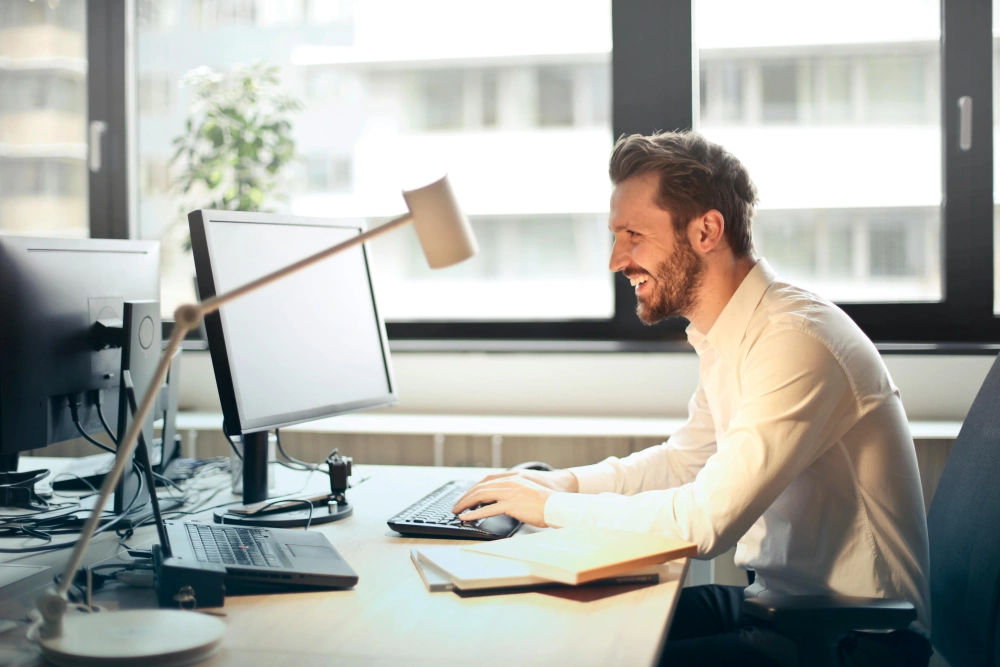 Een lachende man aan zijn computer op de supportdienst van Tickoweb.